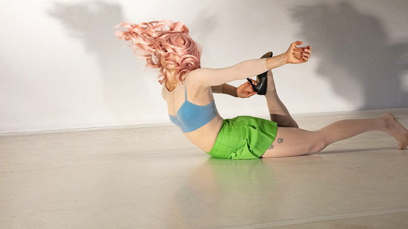 a dancer with pink hair and green skirt is laying on the floor. REPLIKA a choreography by Cie Toula Limnaios performed by Karolina Wyrwal