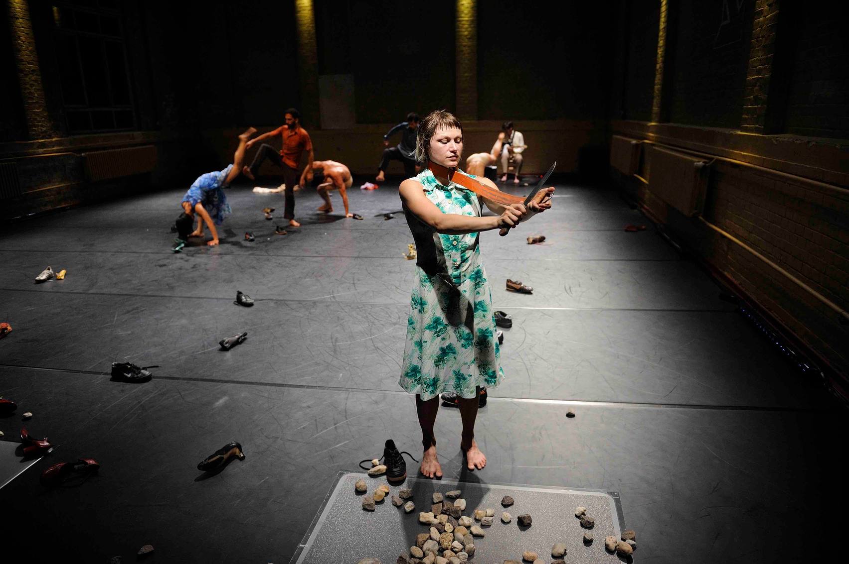 a person in a green dress is standing in front of a group of dancers and she is holding a knife